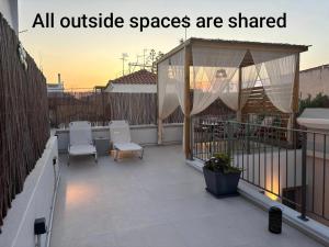a patio with white chairs and a gazebo at Kazarma Central Suites - Apartment Complex in Egina