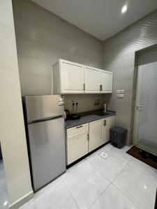 a kitchen with a refrigerator and white cabinets at شقة فندقية غرفتين in Hafr Al Baten