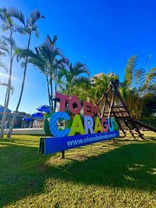 a sign at a resort with palm trees in the background at Hotel Pousada Vivendas do Sol e Mar in Caraguatatuba