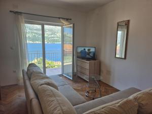 a living room with a couch and a television and a balcony at Apartman Luna Korčula in Korčula