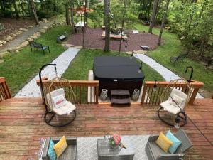 a grill sitting on a wooden deck with two chairs at Majestic Lake Front Chalet in Tobyhanna