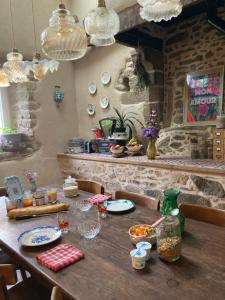 a wooden table with plates and bowls of food on it at Les Reflets Roz in LʼHermitage-Lorge