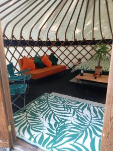 a yurt with couches and a bed and a rug at Bewley Glamping in Wambrook