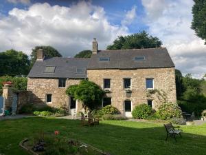 a large stone house with a grass yard at Les Reflets Roz in LʼHermitage-Lorge