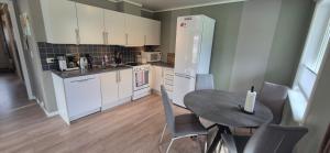 Una cocina con una mesa y un refrigerador blanco. en Bakkegjerdet 48, en Sula