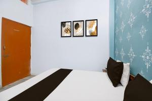 a bedroom with a bed with three pictures on the wall at Hotel O Mahamaya Guest House in Varanasi