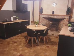 a table and chairs in a kitchen with a fireplace at La cour Royale in Forges-les-Eaux