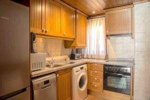 una cucina con armadi in legno, lavatrice e asciugatrice di Apartament familiar de luxe i balcó amb vistes by RURAL D'ÀNEU a València d'Àneu 1 altra foto