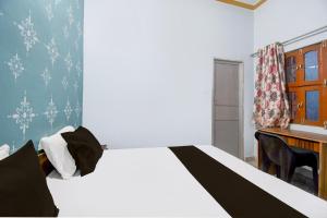 a bedroom with a bed and a desk and a bed sidx sidx sidx at Hotel O Mahamaya Guest House in Varanasi