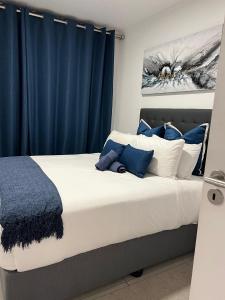 a bedroom with a large bed with blue curtains at Exclusive Two Bedrooms Presidential Suite in Coral Point in Sibaya