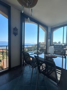 Un comedor con mesa y sillas y ventanas. en Duplex F4-2 balcons face a la mer, en Ajaccio