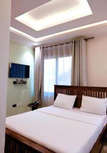 カンパラにあるNeon Hotel Ntindaの窓のある大きな白いベッドのある寝室