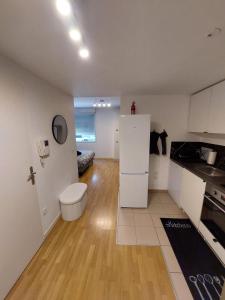a kitchen with white cabinets and a white refrigerator at Cosy Home 4 - Spacieux studio avec parking - 30 min Paris in Cergy