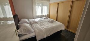 a bedroom with a bed with white sheets and a window at De tepelenburg in Harskamp