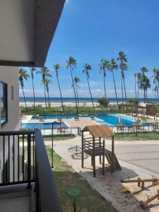 une vue depuis un balcon sur une piscine avec des palmiers dans l'établissement Apartamento pé na areia, à Ilhéus