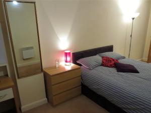 Un dormitorio con una cama con una vela rosa sobre una cómoda. en Echo apartment Sunderland, en Sunderland