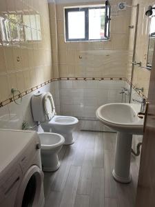 a bathroom with two toilets and a sink and a toilet istg at Rei's Apartment 2 in Tirana