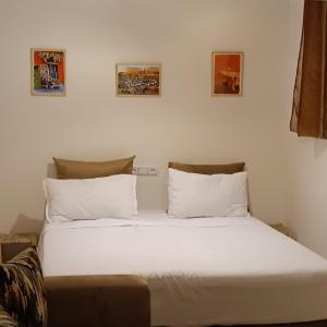 a white bed in a room with pictures on the wall at Dar Bellaji l Bed & Breakfast in Medina l Rooftop Koutoubia in Marrakech