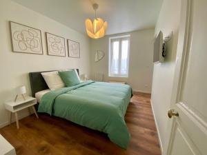een slaapkamer met een bed met een groene deken bij Haut Chatelet in Orléans