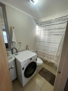 a bathroom with a toilet and a washing machine at Cabaña céntrica con vista al lago in Puerto Varas