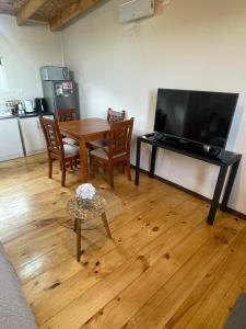 a living room with a wooden table and a television at Cabaña céntrica con vista al lago in Puerto Varas