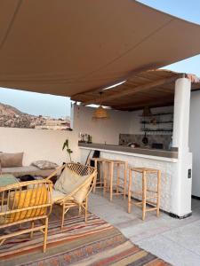 a patio with chairs and a table and a bar at Azul Berg Hostel in Tamraght Ouzdar
