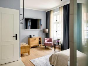 a bedroom with a bed and a chair and a tv at Boutiquehotel Petuh am Hafen - adults only in Flensburg