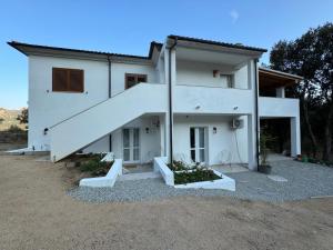a white house with a staircase in front of it at Domo s eliga in Padru
