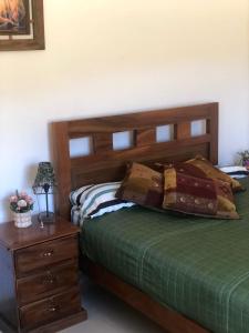 Schlafzimmer mit einem Bett mit einem Kopfteil aus Holz und einem Tisch in der Unterkunft El Rincón de Nukuri by Looking Samaipata in Samaipata