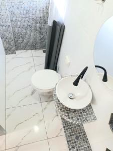 een witte badkamer met een toilet en een wastafel bij Guará Apart 2 in Guaratuba