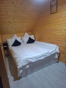 a bedroom with a white bed in a wooden cabin at Căsuța Piatra Craiului in Zărneşti