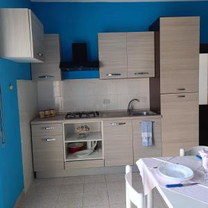 a kitchen with wooden cabinets and a sink and a table at Azzurro relax in Badesi +7 photos