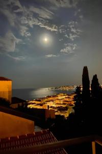 a view of a city at night with the moon at A SCANDINAVIAN EXCLUSIVE DESIGN RESIDENCE - PREMIUM LIVING - TWO PRIVATE BALCONIES w PANORAMIC SEA VIEW - 3 MIN TO BEACH - PARKING in Menton