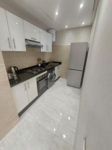 a kitchen with white cabinets and a refrigerator at Appartement centre ville in Oulad Akkou