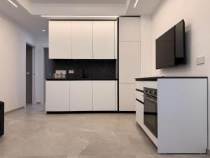 a kitchen with white cabinets and a flat screen tv at Residenza Milla in Alassio