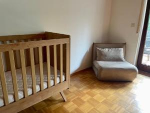 a crib and a chair in a room at Odw homes - Wohnung im Landhaus mit Garten in Trösel +23 photos