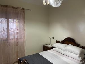 a bedroom with a bed with a chandelier and a window at BLANCA BEACH- بلانكا بيتش سكن مشترك غرفة مزدوجة مكيفة لدى الساكن في I COLOCATION I Chambre double climatisée chez l'habitant dans une résidence pieds dans l'eau I FLAT SHARE I Air conditioned double room in a host's home within a waterfront residence in Sidi Rahal +6 photos