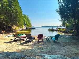 a group of chairs sitting on a beach next to the water at 1463 Big Rideau in Portland