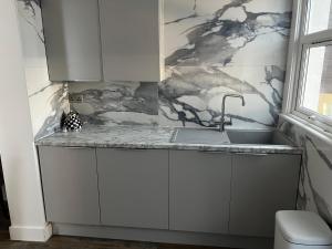a kitchen with white cabinets and a sink at Southend Luxe Retreat in Southend-on-Sea +69 photos