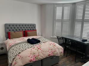 a bedroom with a bed and a desk and windows at Southend Luxe Retreat in Southend-on-Sea