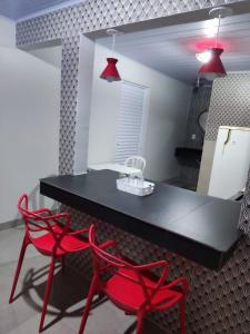 un tavolo nero e due sedie rosse in una stanza di Residencial Franco Casa 01 a Primavera do Leste
