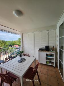 ein Esszimmer mit einem Tisch und Stühlen sowie einem Balkon in der Unterkunft Ti coco luce studio à Sainte Luce dans village de vacances in Sainte-Luce