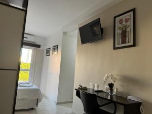 a room with a table and a tv on the wall at City Bauru - Studio completo em frente a USP, FOB - Centrinho e HC de Bauru in Bauru