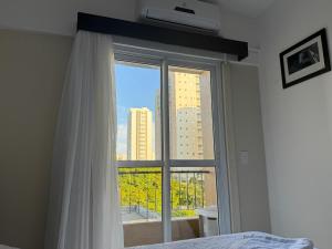 a bedroom with a window with a view of a building at City Bauru - Studio completo em frente a USP, FOB - Centrinho e HC de Bauru in Bauru