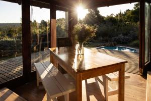 a wooden table with a vase of flowers on a deck at Forest Song in Plettenberg Bay