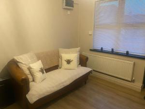 a couch with pillows sitting in a room with a window at Castletroy Apartment in Limerick