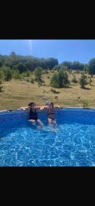 two people are sitting in a swimming pool at Jezerina in Šavnik