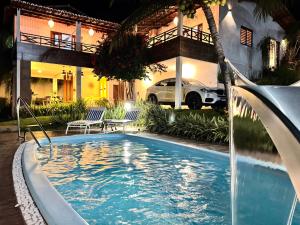 a swimming pool in front of a house with a car at Casa dos Girassóis in Pipa