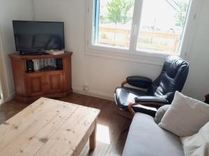 a living room with a couch and a tv and a table at Le calme près de la ville in Saumur