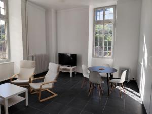 a room with a table and chairs and a tv at O'Couvent - Appartement 131 - 2 chambres - 90 m2 - Troisième étage in Salins-les-Bains
